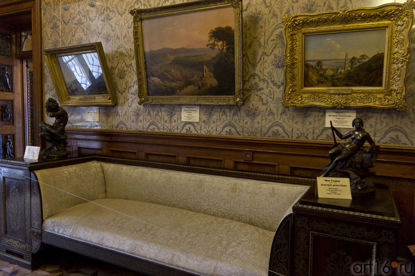 Фрагмент интерьера Ситцевой комнаты: диван, скульптуры и пейзажные полотна на стене